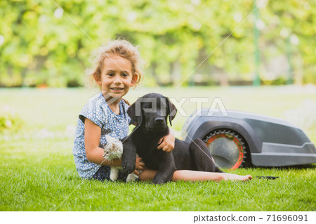 Cute liitle girl with her pets on freshly mowed lawn Cute liitle girl with her pets on freshly mowed lawn 71696091
