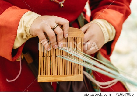 Weaving craft. Woman in traditional dress works with hands 71697090