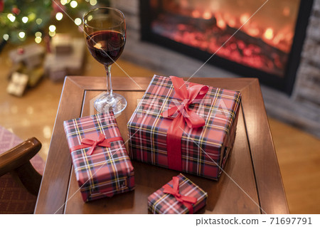 Armchair with plaid, packing gift boxes for family and glass of wine near christmas tree and fireplace. Top view Armchair with plaid, packing gift boxes for family and glass of wine near christmas tree and fireplace. Top view 71697791