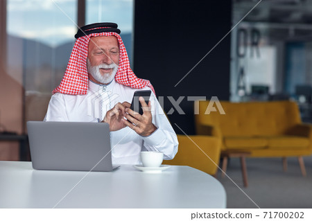 Arab businessman laptop computer in modern office using phone 71700202