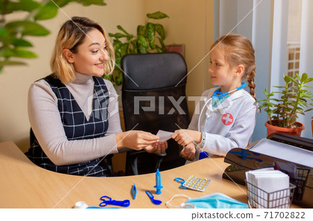 Paediatrician doctor examining a child in comfortabe medical office. Little girl playing pretends like doctor for woman 71702822