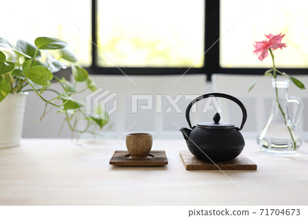 Black traditional teapot with wooden cup and rose flower on pale brown wooden table Black traditional teapot with wooden cup and rose flower on pale brown wooden table 71704673
