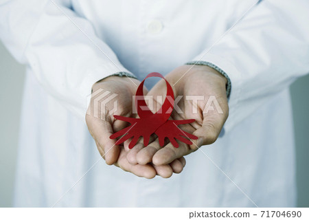 doctor with a red awareness ribbon in his hands 71704690