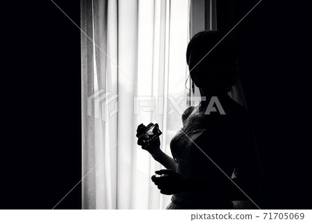 silhouette of an elegant bride at window with perfume silhouette of an elegant bride at window with perfume 71705069