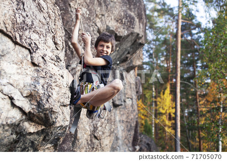 cute teen kid climbing on rock with insurance, lifestyle sport people concept cute teen kid climbing on rock with insurance, lifestyle sport people concept 71705070