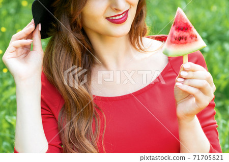 Fashionable young woman is holding a slice of watermelon. 71705821