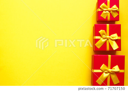 three bright red gift boxes on yellow background 71707150