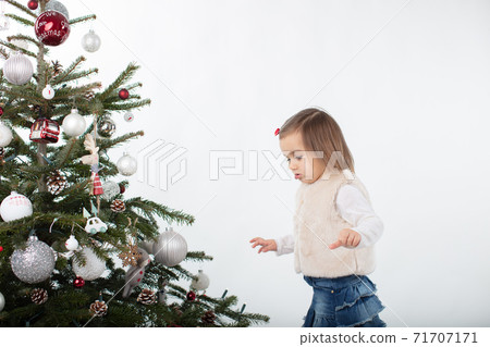 Cute toddler girl carefully walking around the Christmas tree 71707171