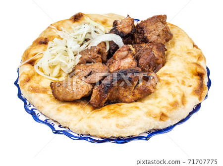 portion of kebab on flatbread on plate isolated 71707775