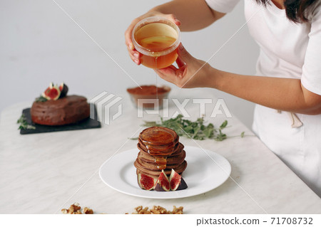Cook pours honey on the pancakes. 71708732