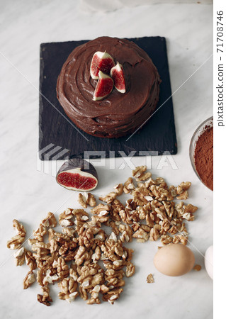 Confectioner decorates a chocolate cake with figs. Confectioner decorates a chocolate cake with figs. 71708746