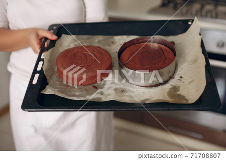 Confectioner takes the finished cake out of the oven. 71708807