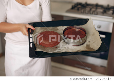 Confectioner takes the finished cake out of the oven. Confectioner takes the finished cake out of the oven. 71708812