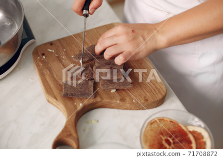 Confectioner cuts chocolate on a wooden board. Confectioner cuts chocolate on a wooden board. 71708872