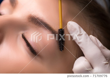 Permanent eyebrow makeup. Cosmetologist applying tattooing of eyebrows. Permanent eyebrow makeup. Cosmetologist applying tattooing of eyebrows. 71709776