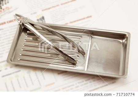 Dental forceps is lying in the medical tray. Dental forceps is lying in the medical tray. 71710774