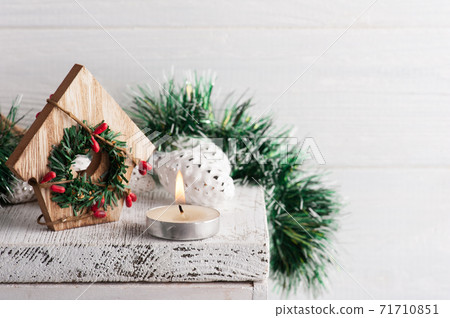 Christmas decoration with toy house and lit candle Christmas decoration with toy house and lit candle 71710851