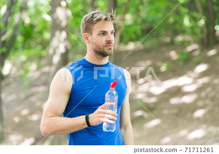 Healthy lifestyle. Athlete drink water after training in park.  71711261