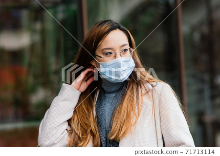 Asian woman with surgical mask face protection. She commutes between home and workplace in the city Asian woman with surgical mask face protection. She commutes between home and workplace in the city 71713114
