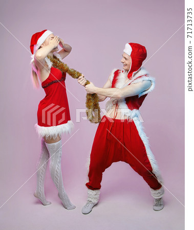 guy and girl in Santa Claus costumes. photo session in the Studio. Christmas and New year concept guy and girl in Santa Claus costumes. photo session in the Studio. Christmas and New year concept 71713735