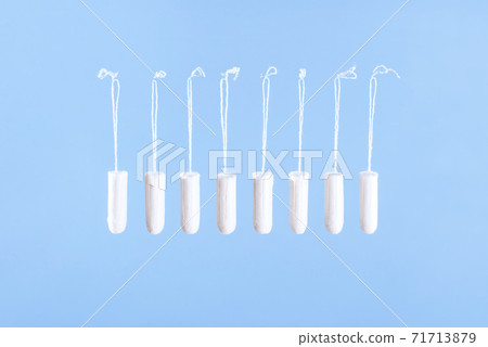 Flying tampons. Menstrual period concept. Woman hygiene protection. Women's health. Cotton tampons on blue background. Front view. Conceptual minimal still life. Flying tampons. Menstrual period concept. Woman hygiene protection. Women's health. Cotton tampons on blue background. Front view. Conceptual minimal still life. 71713879