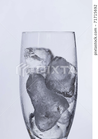 在一塊玻璃的冰塊用水在白色背景滴下 在一塊玻璃的冰塊用水在白色背景滴下 71715692