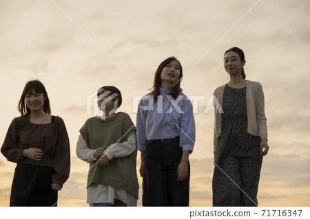四名婦女在黃昏時沿著海邊散步 71716347