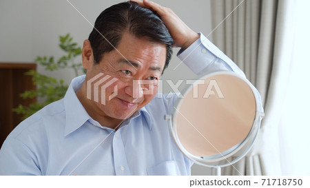 Middle-aged man trimming hair Middle-aged man trimming hair 71718750