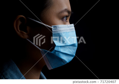 Asian woman wearing protective mask isolated over background. Low key. 71720407