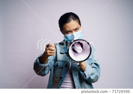 Asian woman wearing protective face mask shouting with megaphone isolated over white background. 71720500