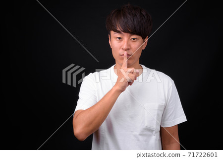 Young handsome Asian man against black background Young handsome Asian man against black background 71722601