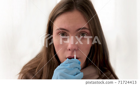 Woman takes swab from nasal mucosa using medical tampon 71724413