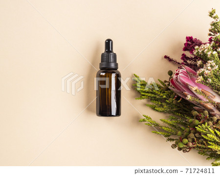 Essential oil bottle among flowers. Beauty product 71724811