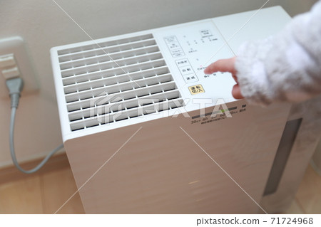 Girl turning on the vaporizing humidifier 71724968