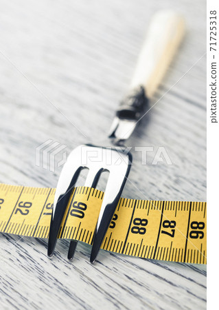Yellow centimeter wrapped dessert fork on an old wooden table with the number 90. The concept of restriction in food for a slim figure with parameters 36 24 36 or 90 60 90 Yellow centimeter wrapped dessert fork on an old wooden table with the number 90. The concept of restriction in food for a slim figure with parameters 36 24 36 or 90 60 90 71725318