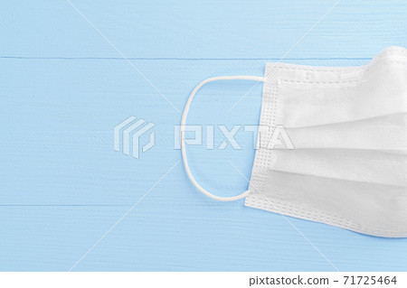 Medical protective white mask on a wooden light blue background. Half. Copyspace. Close-up. Coronavirus Remedies Concept 71725464