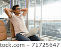 A handsome man in a casual style is worry free expression looking far to the copy space, Optimistic man put laptop over his leg while open his arm to relax from stress work. Work anywhere concept. 71725647