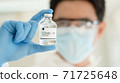 scientist in laboratory with bottle of covid-19 vaccine 71725648