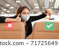 Young Woman in a protective mask point her finger to the right green sign to support social distancing 71725649