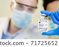 scientist in laboratory with bottle of covid-19 vaccine 71725652