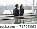 Business woman wearing face mask using smartphone while standing on escalator with businessman nearby, business trip and stay safe concept. 71725663