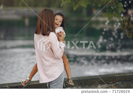 Elegant mother with daughter walks by the water 71726029
