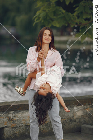 Elegant mother with daughter walks by the water 71726042