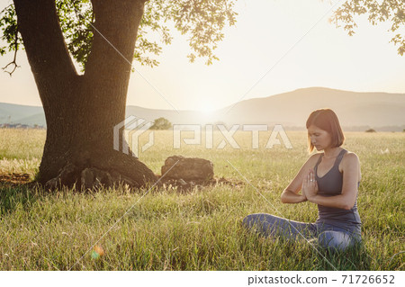 Attractive woman practices yoga in nature in summer. Attractive woman practices yoga in nature in summer. 71726652