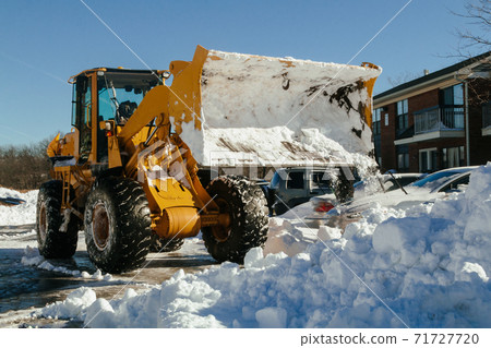 Mechanized tractor for snow removal is parked on a city street after snowfall 71727720