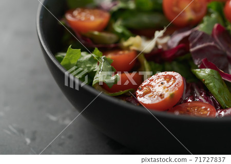 Salad with green and purple leaves and cherry tomatoes in black bowl Salad with green and purple leaves and cherry tomatoes in black bowl 71727837