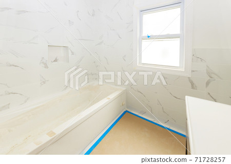 Bathroom with tiled walls installing shower and sink, is in the apartment that is under construction of home 71728257