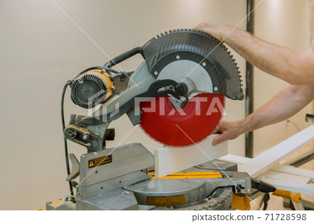 A worker cuts a wooden molding board at a construction 71728598