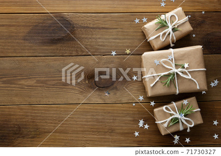 Christmas mock up with gift boxes wrapped with brown kraft paper over wooden board. Christmas mock up with gift boxes wrapped with brown kraft paper over wooden board. 71730327