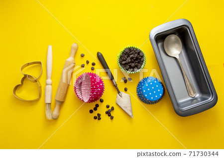 Abstract baking concept. Cooking utensils, rolling pin, cupcake molds, cookies cutters over yellow background flat lay Abstract baking concept. Cooking utensils, rolling pin, cupcake molds, cookies cutters over yellow background flat lay 71730344